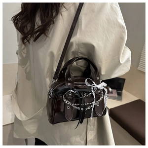 Detail of dark brown glossy leather handbag with silver chains and lace bows decoration