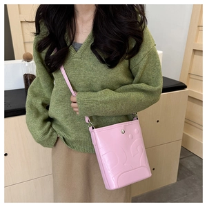 Gros plan du sac seau en cuir rose avec logo DG embossé et fermoir métallique argenté