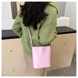 Vue arrière du modèle portant un sac à bandoulière rose avec texture en relief et fermoir