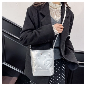 Détail du sac seau argenté avec texture gaufrée en 3D et fine bandoulière réglable