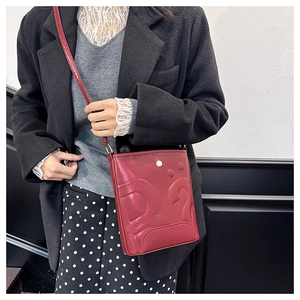Détail du sac seau rouge avec logo D2 en relief et fermoir métallique porté par un mannequin