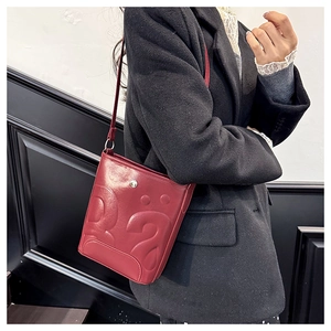 Détail du sac seau en cuir PU rouge avec motif point d'interrogation sur manteau noir