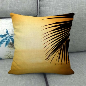 Linen pillowcase with tropical palm leaf silhouette and sunset print on gray sofa