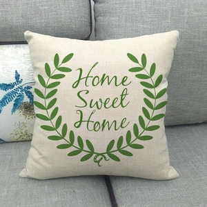Close-up of linen cushion cover with green wreath and Home Sweet Home text on grey sofa