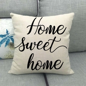 Detail of linen cushion cover with black Home Sweet Home script on a grey fabric sofa