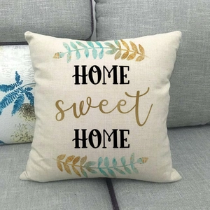 Detail of linen pillowcase with 'HOME sweet HOME' print on a grey fabric sofa