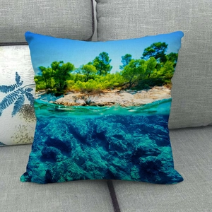 Funda de cojín de lino con paisaje de playa tropical sobre un sofá de tela gris