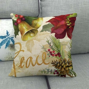 Housse de coussin Noël en lin avec texte Peace doré et poinsettia sur un canapé gris