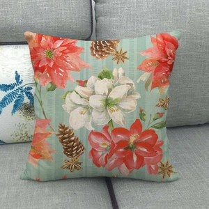 Détail de housse de coussin en lin avec poinsettia et pommes de pin sur canapé