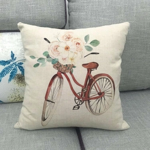 Close-up of linen pillow cover featuring a red vintage bicycle with flower basket on sofa