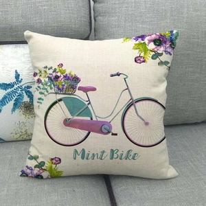 Linen pillowcase with vintage mint bike and purple floral pattern on a gray sofa