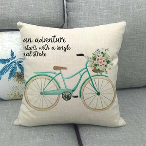 Detailed close-up of watercolor bicycle and floral print on a linen throw pillow cover.
