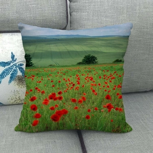 Close-up of linen cushion cover with red poppy field and green landscape pattern