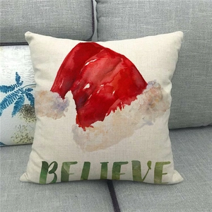 Detail of linen Christmas pillow cover with red Santa hat and Believe artistic text