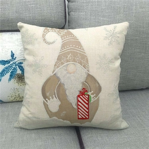 Close-up of linen pillow cover featuring a Nordic Christmas gnome with gift box on sofa