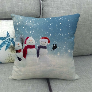 Detail of linen Christmas pillowcase with three cute snowmen on a grey sofa