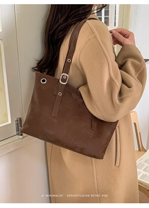 Detail of dark brown leather tote bag showing metal eyelets and adjustable buckle strap