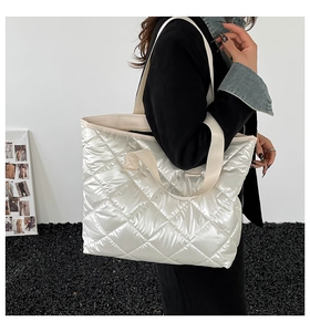 Détail du sac fourre-tout argenté matelassé montrant le nylon brillant et les surpiqûres