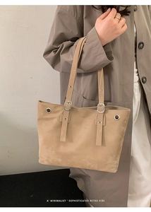 Detail of light brown suede tote bag featuring silver eyelets and adjustable shoulder strap