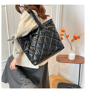 Seitenansicht einer großen schwarzen gesteppten Shopper-Tasche am Modell zu Hause