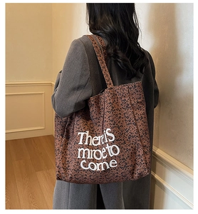 Detail of leopard print tote bag featuring white letter printing and canvas texture