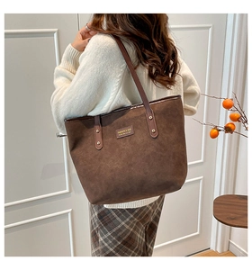 Detail view of the brown suede tote bag with leather tag and golden rivet strap on a model