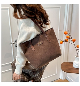 Detalle del bolso tote vintage en ante marrón oscuro con correas de cuero y remaches