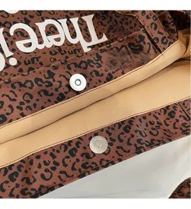 Detail of leopard print canvas tote bag featuring a secure magnetic snap closure and inner lining