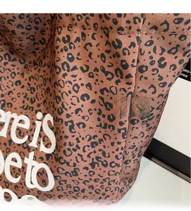 Close-up of leopard print tote bag featuring heavy canvas texture and bold white lettering