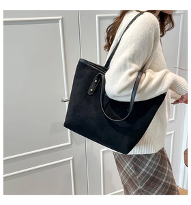 Close-up of black suede tote bag featuring metallic rivet details on the handle
