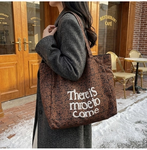 Street style shot of a vintage leopard print canvas tote bag with white text detail