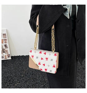 Detail of sweet small square bag with cherry and bear print and gold chain strap