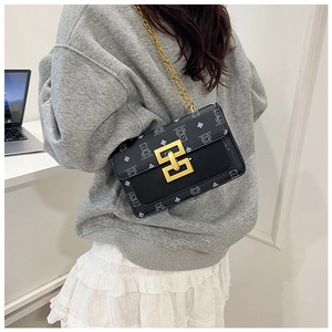 Détail d'un petit sac bandoulière noir avec chaîne dorée porté par un mannequin chic