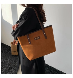 Detailed shoulder view of the brown faux suede tote bag with leather straps on a model