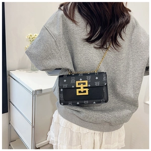 Détail du sac bandoulière en cuir noir avec chaîne dorée et motif d'ours élégant