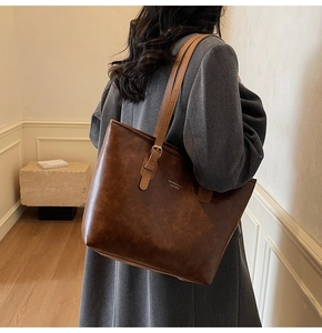 Deep brown vintage tote bag in textured leather worn with a grey wool coat detail