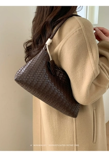 Detail of dark brown woven leather underarm bag with decorative knot on shoulder strap