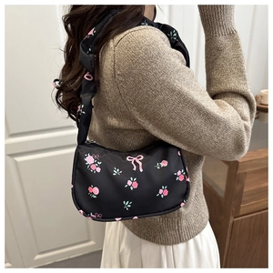 Detail of black underarm bag with pink rose print and ruffled shoulder strap