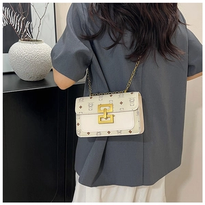Détail d'un sac bandoulière beige avec motif d'ours et boucle géométrique dorée