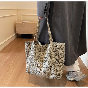 Detail shot of leopard print canvas tote bag with white There's more to come lettering