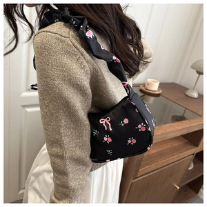 Détail du sac porté épaule à fleurs avec roses roses et finition en satin noir soyeux
