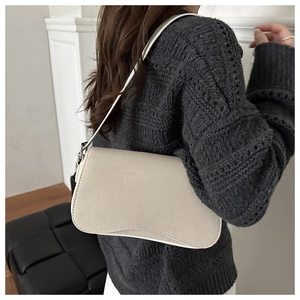 Minimalist beige leather underarm bag shown on shoulder in a lifestyle setting