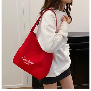 Detailed shot of large red canvas tote bag with C'est la vie print on white sweatshirt