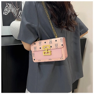 Sac bandoulière rose avec motif ours et chaîne dorée sur une veste de costume grise