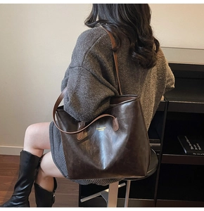 Detail of vintage brown leather tote bag with dual straps and elegant gold lettering