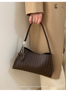 Détail de la texture tressée du sac à bandoulière marron foncé avec charme nœud blanc