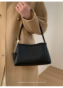 Détail du sac à main noir tressé avec design trapèze minimaliste et poignée délicate