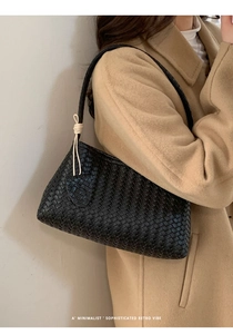 Détail d'un sac à bandoulière en cuir tressé noir avec un nœud contrastant sur modèle