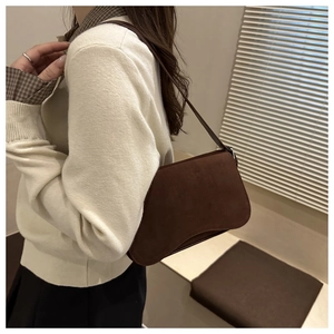 Detail of vintage brown suede shoulder bag showing smooth texture and leather strap