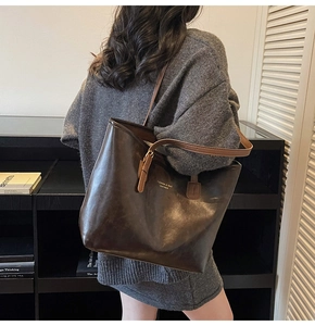 Detail of vintage oil wax leather tote bag featuring gold lettering and adjustable strap